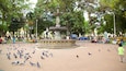 Un parque con una fuente central, rodeado de árboles y bancos.