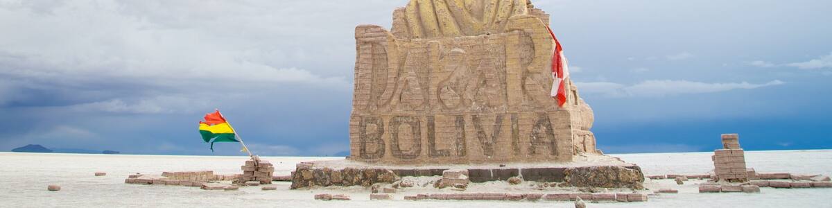 Une grande statue de pierre portant l’inscription « BOLIVIE » et un mât sur lequel flotte un drapeau.