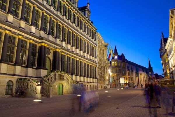 Een historische Europese straat in de schemering, met verlichte gebouwen en een heldere lucht.