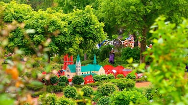 Un pequeño pueblo con edificios en miniatura y una iglesia, rodeado de abundante vegetación.
