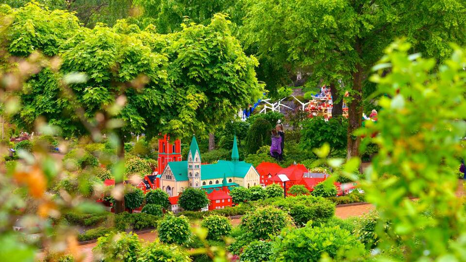 A miniature village with model buildings and a church, surrounded by lush greenery.