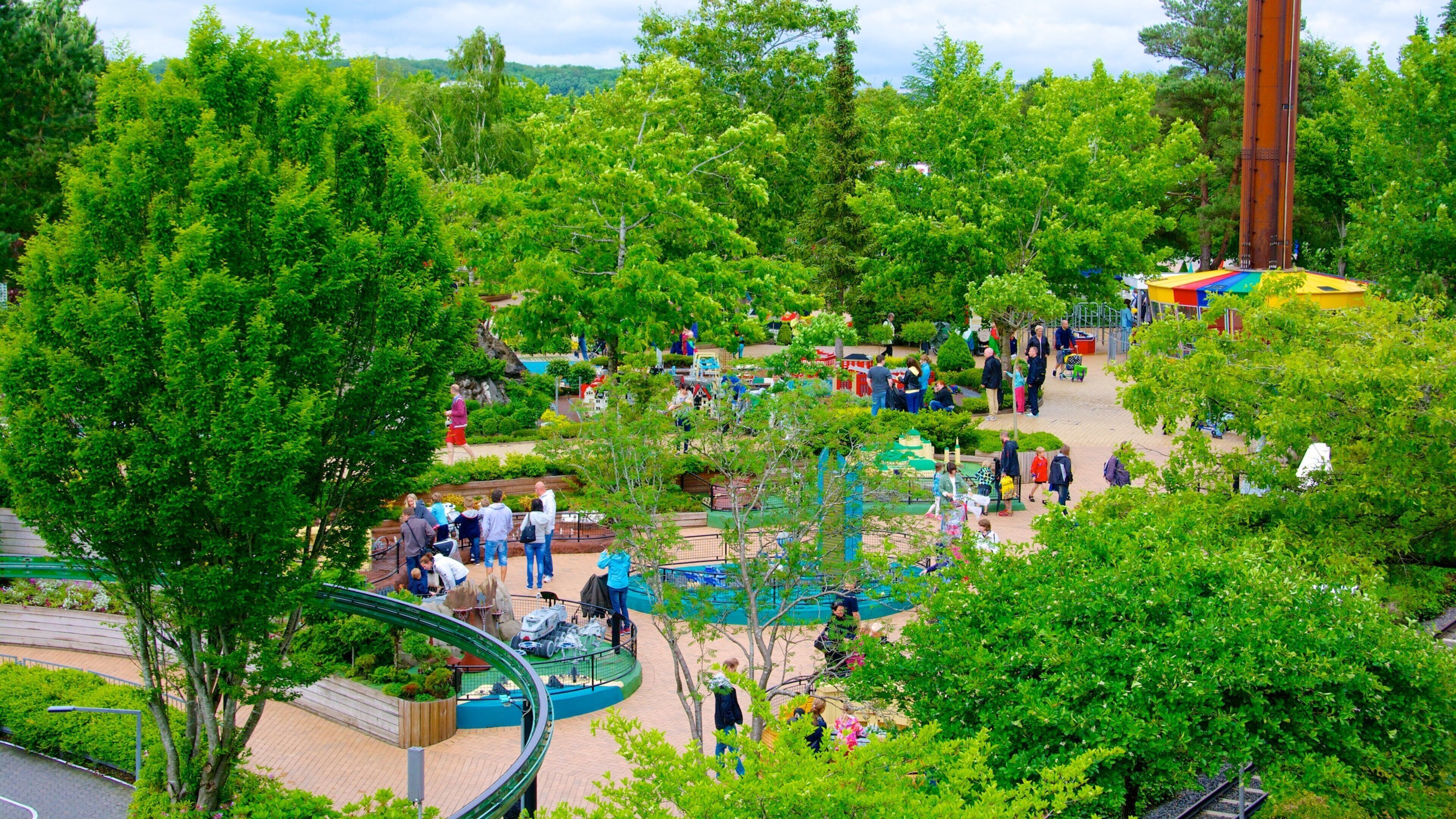 A park with green trees, a playground, and a tall structure.