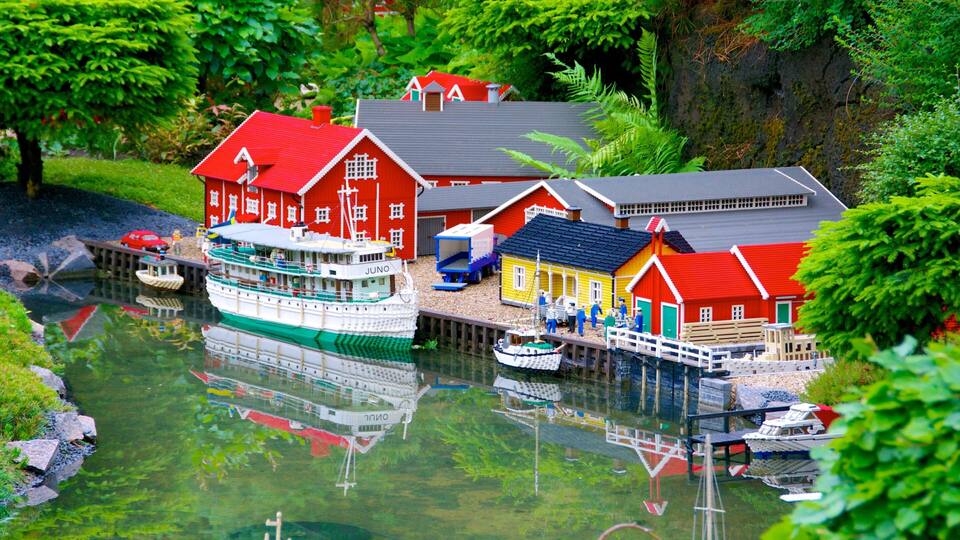 A model of a harbor with a large white and green boat, red and yellow buildings, and a dock.