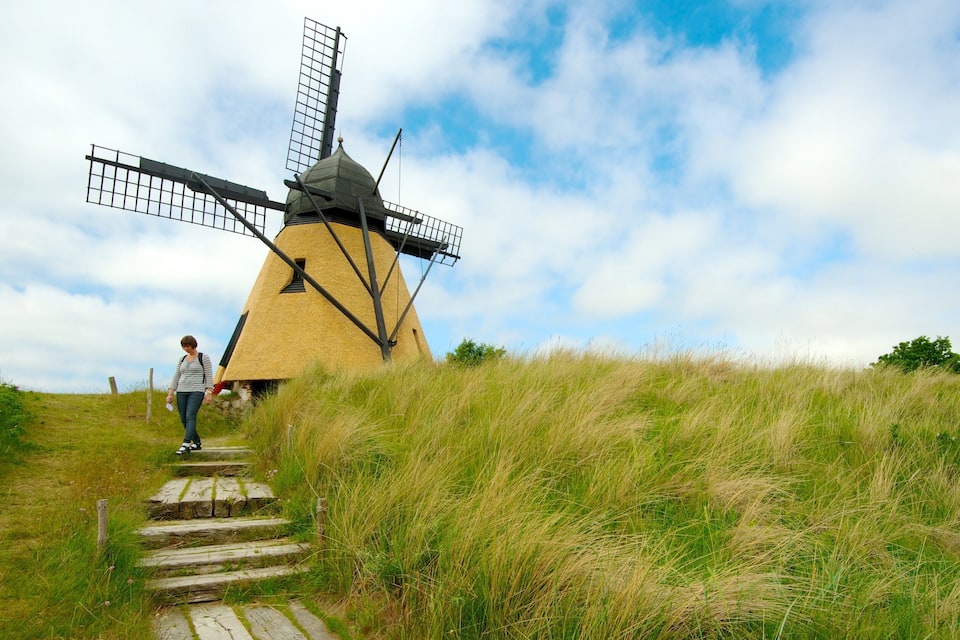A windmill on a grassy hill with a clear sky.