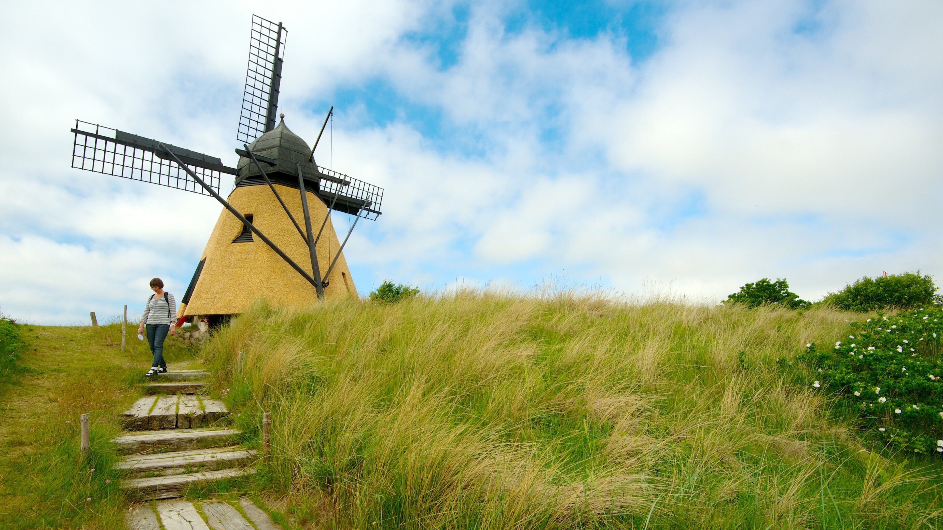 A windmill on a grassy hill with a clear sky.