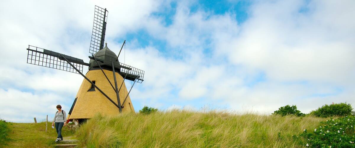 A windmill on a grassy hill with a clear sky.