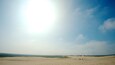 A desert landscape with sand dunes and a few people walking in the distance.