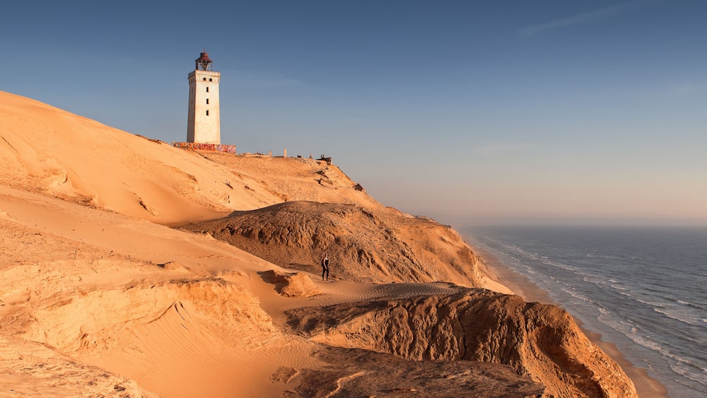 Aerial view of the giant sand dunes with the famous lighthouse on the top of a hill. Rubjerg Knude Lighthouse, Lønstrup in North Jutland in Denmark, Skagerrak, North Sea