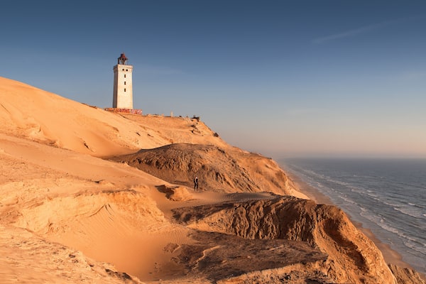 Aerial view of the giant sand dunes with the famous lighthouse on the top of a hill. Rubjerg Knude Lighthouse, Lønstrup in North Jutland in Denmark, Skagerrak, North Sea