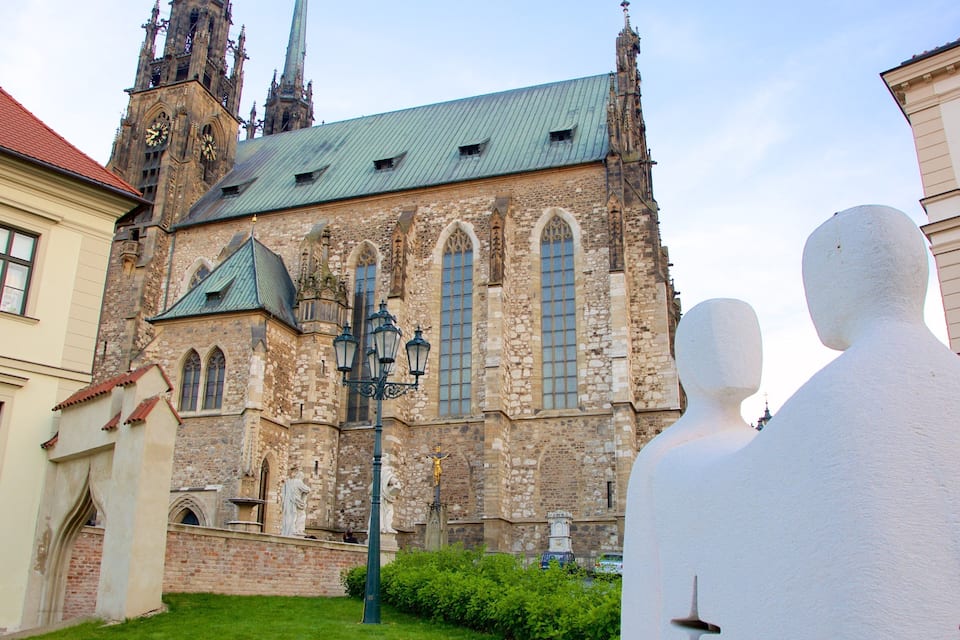 A historic church with a tall spire and clock tower, surrounded by buildings and greenery.
