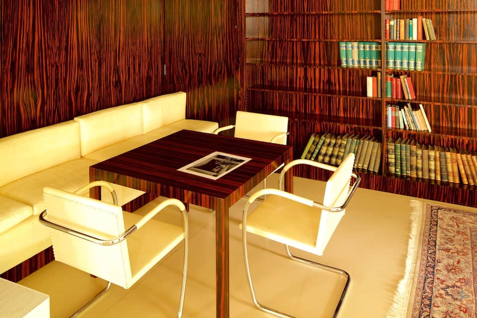 A cozy reading nook with a wooden bookshelf, a leather sofa, and a small table.