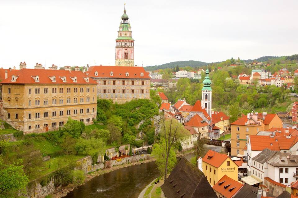 A historic town with a prominent tower, a river, and lush greenery.