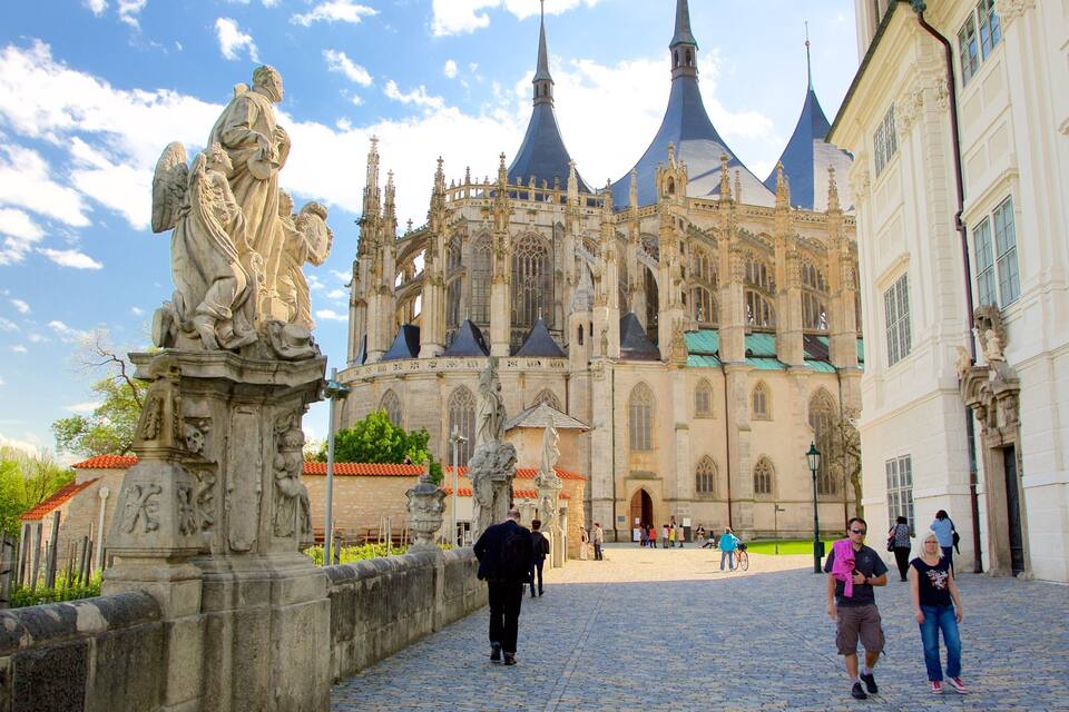Een historische kathedraal met gedetailleerde gotische architectuur en een standbeeld van een heilige op een brug.