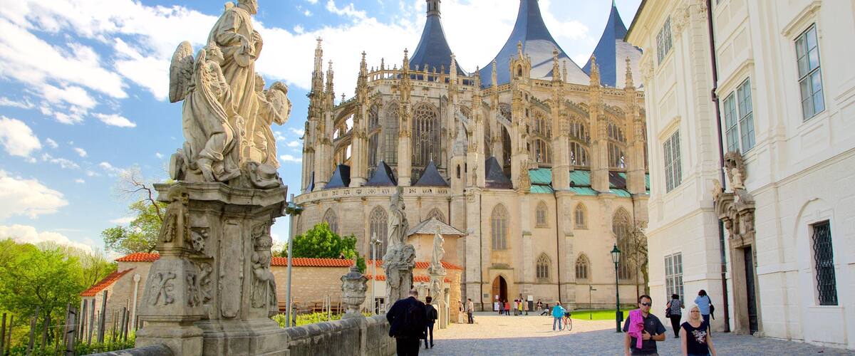 A historic cathedral with intricate Gothic architecture and a statue of a saint on a bridge.