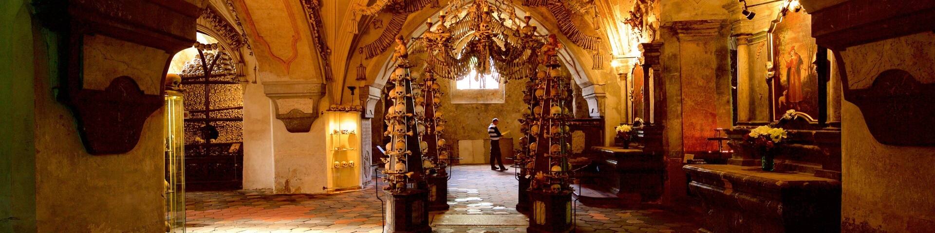 An ornate chapel interior with skull-adorned ceilings and a central chandelier.