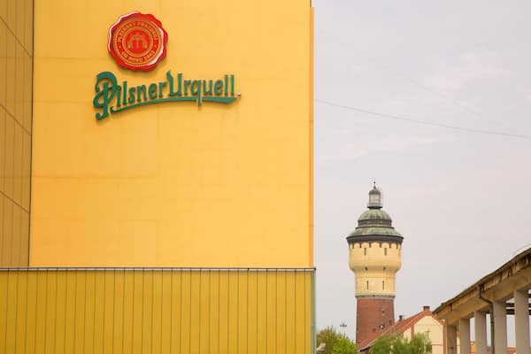 A yellow building with a sign reading "PilsnerUrquell" and a tower in the background.