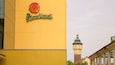 A yellow building with a sign reading "PilsnerUrquell" and a tower in the background.