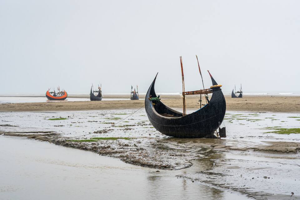 A boat stranded on a muddy beach with several other boats in the background.