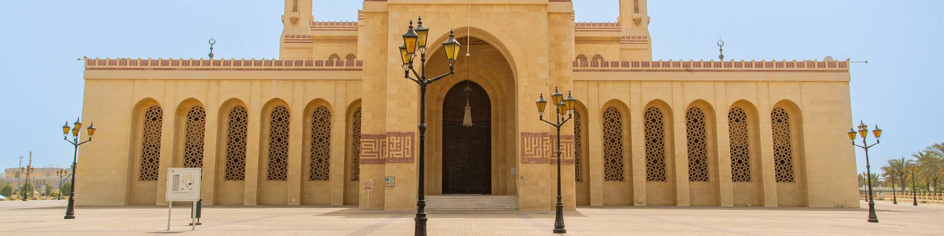 A large mosque with two minarets, a central dome, and a courtyard with patterned paving.
