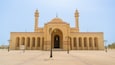 A large mosque with two minarets, a central dome, and a courtyard with patterned paving.