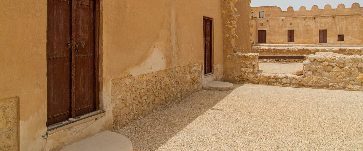 A courtyard with stone walls and wooden doors.