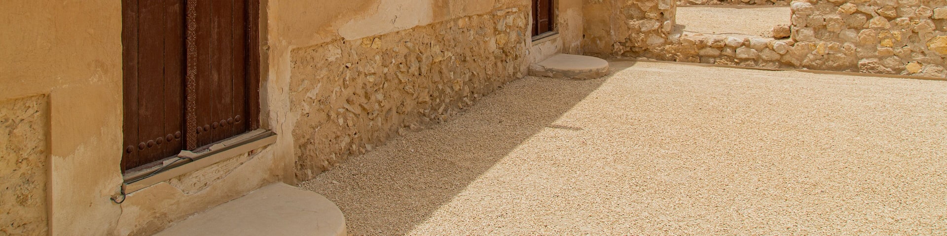 A courtyard with stone walls and wooden doors.