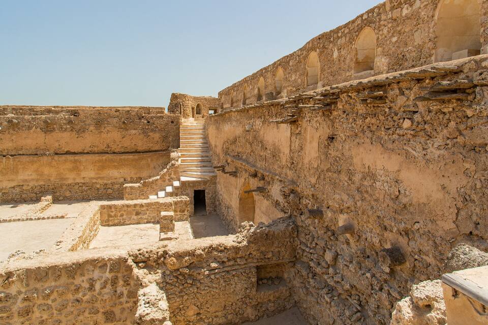 Ancient ruins with stone steps leading up to an arched doorway.