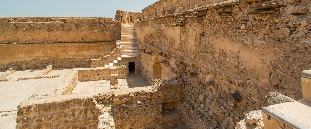 Ancient ruins with stone steps leading up to an arched doorway.