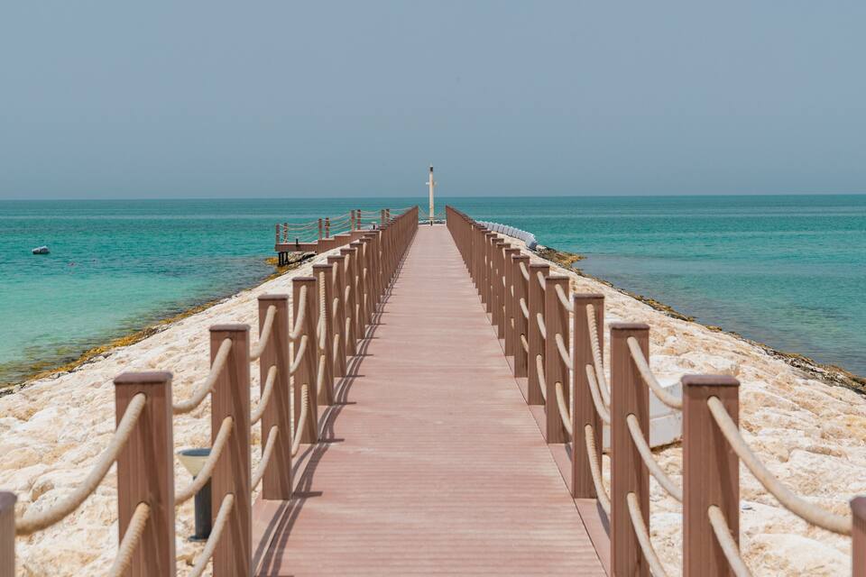 Un muelle de madera que se adentra en un mar turquesa bajo cielos despejados.