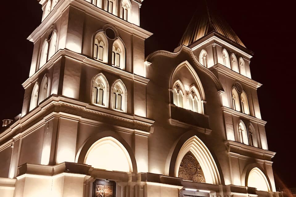 A grand, illuminated building with multiple arched windows and a prominent dome.