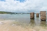 A beach with clear water, boats, and stone pillars.