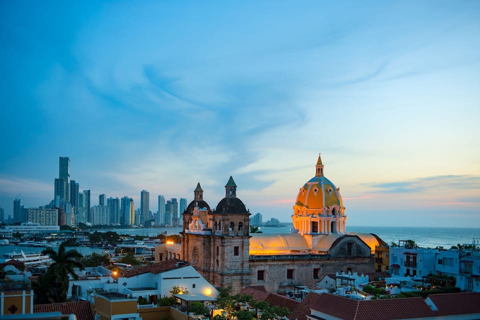 A coastal cityscape with a prominent cathedral and modern skyscrapers.