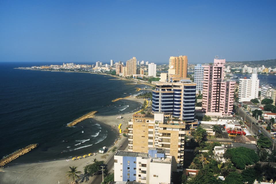 A coastal cityscape with a beach, high-rise buildings, and a clear blue sky.