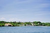 A coastal town with a white building with a red roof, surrounded by lush greenery and palm trees.