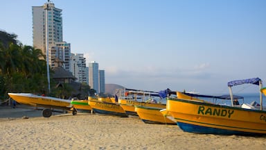 Uma fileira de barcos amarelos e azuis numa praia arenosa, com palmeiras e edifícios altos ao fundo.