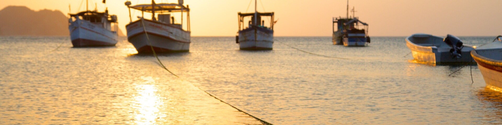 Praia Taganga mostrando canoagem, um pôr do sol e uma baía ou porto