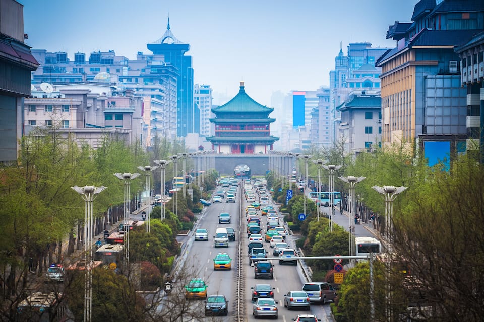 A busy urban street with a traditional building in the center.