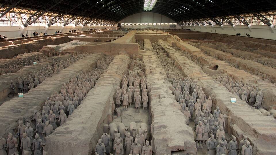 A large indoor exhibition of terracotta soldiers arranged in rows.