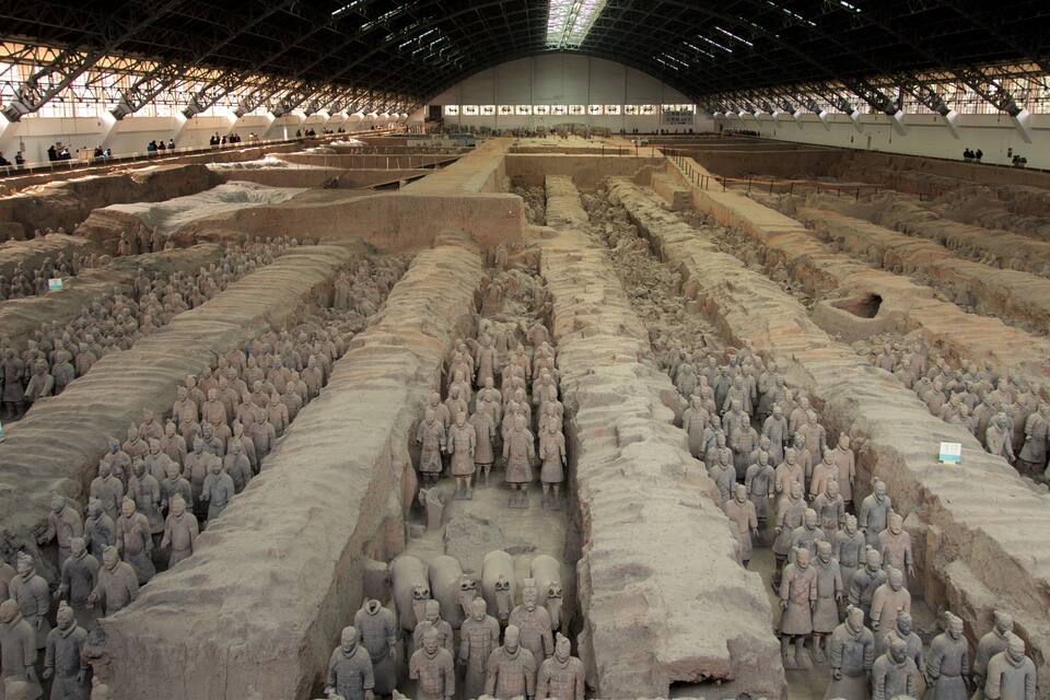 A large indoor exhibition of terracotta soldiers arranged in rows.