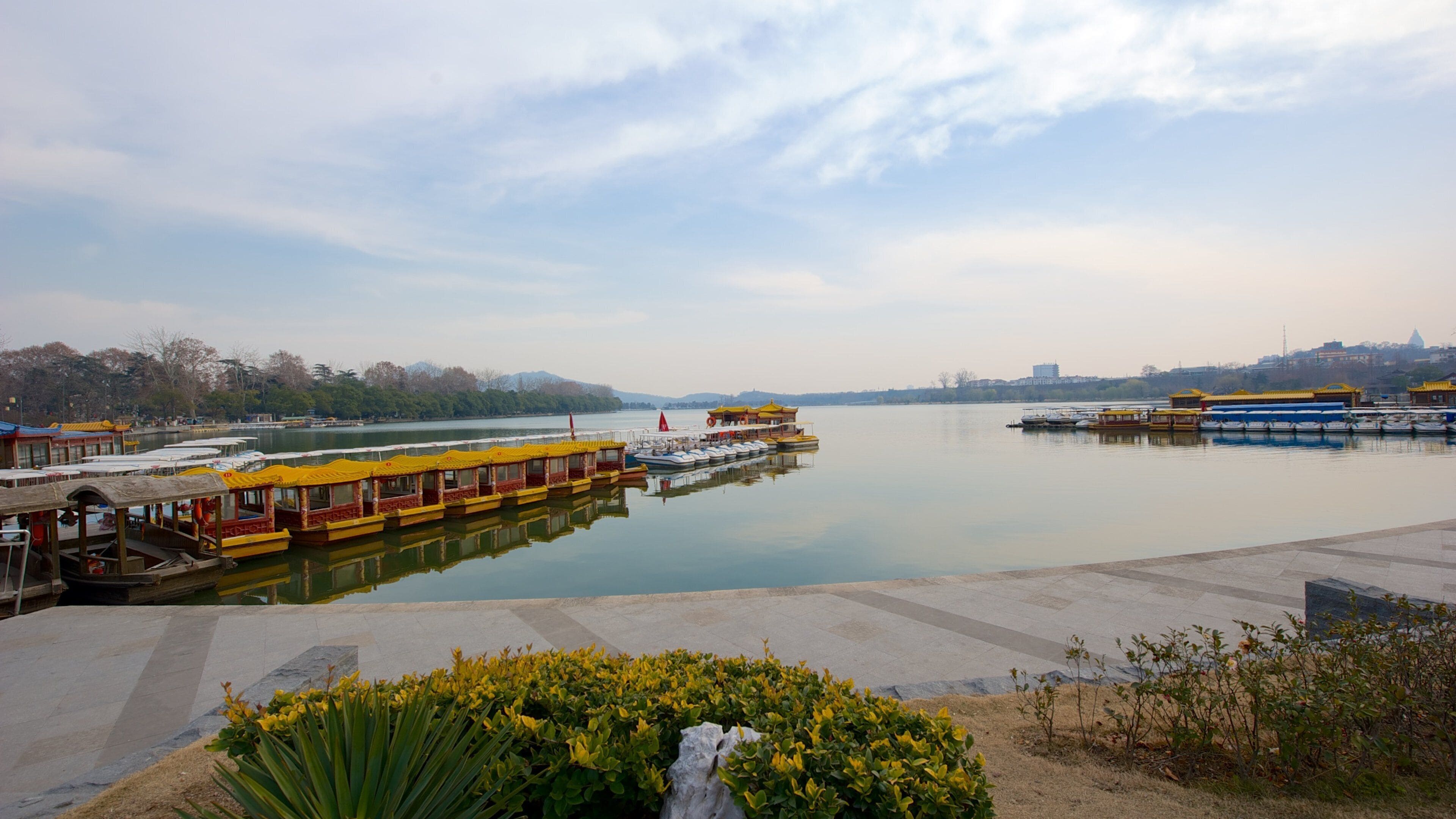 A calm river with yellow and blue boats docked at the pier.