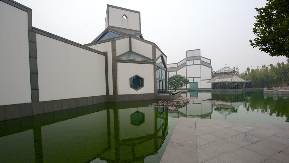 Ein modernes Gebäude mit einem reflektierenden Wasserspiel davor.