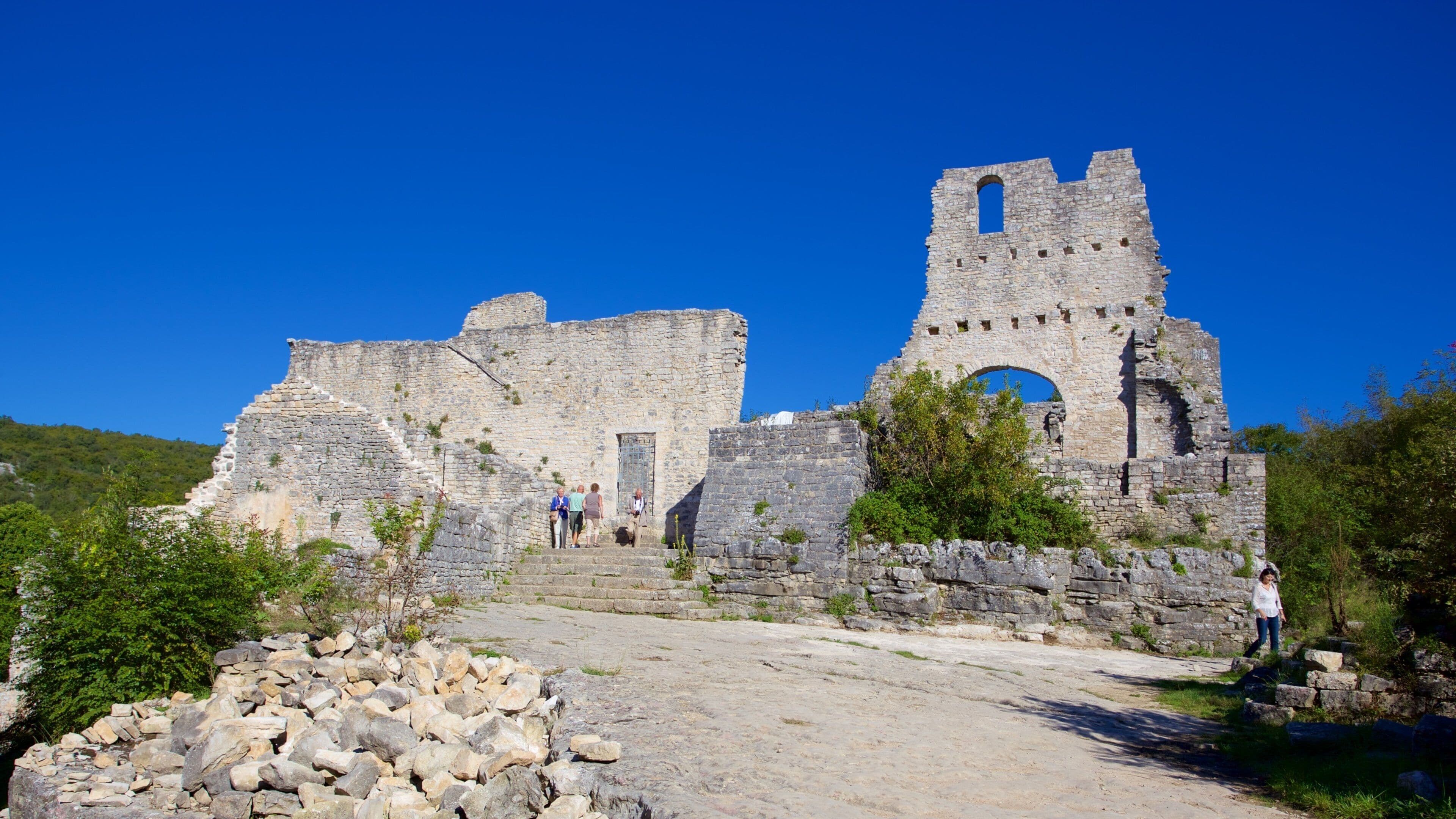 An ancient stone structure with a large arched doorway and a tower.