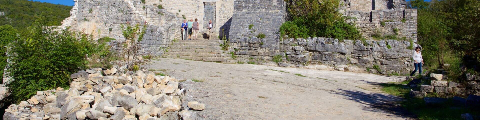 An ancient stone structure with a large arched doorway and a tower.
