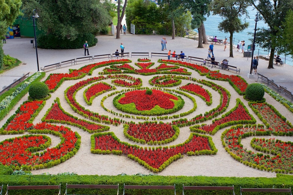 Un jardín de flores cuidadosamente diseñado con patrones geométricos y bancos a lo largo de un paseo marítimo.