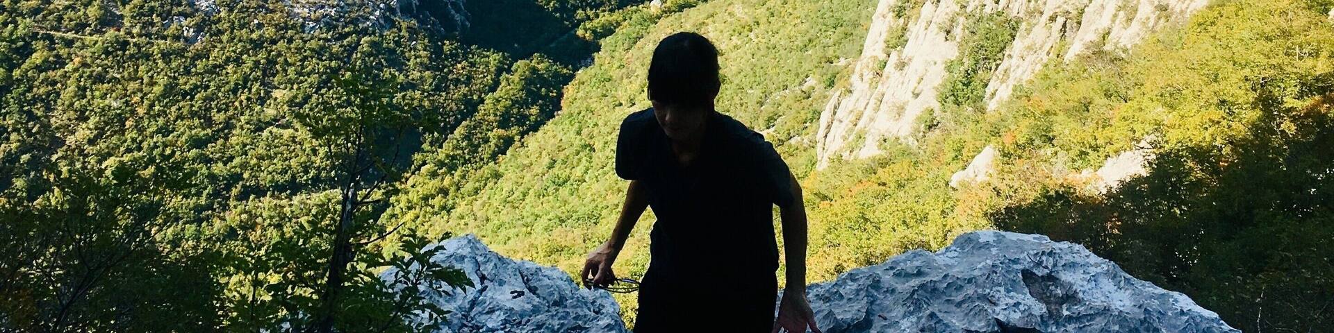 A person hiking on a rocky trail with a mountainous landscape in the background.