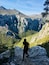 Una persona camina por un sendero pedregoso con un paisaje montañoso de fondo.