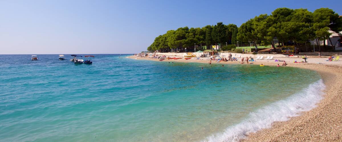 A beach with clear turquoise water, boats, and people relaxing on the sand.