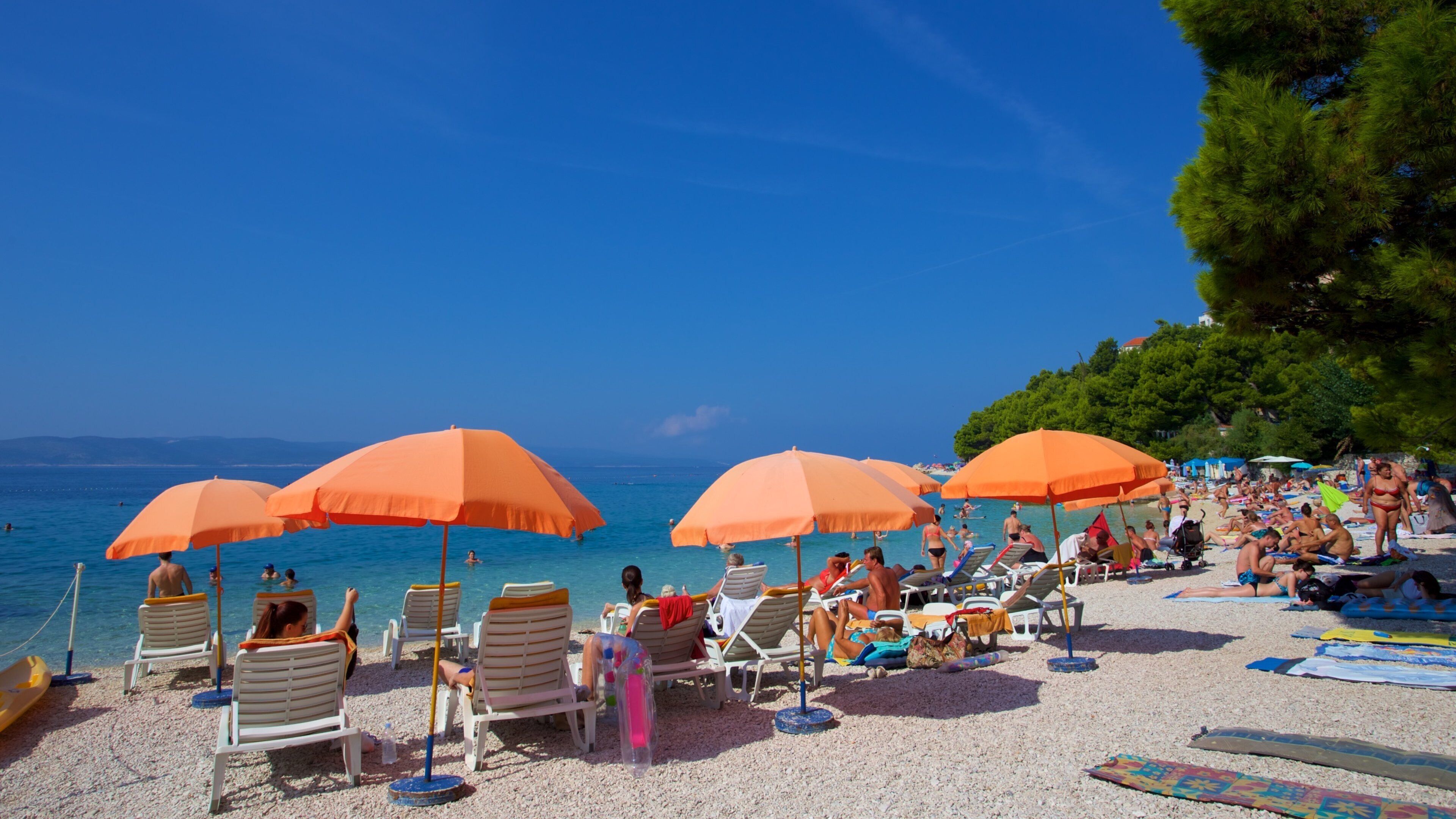 Baska Voda strand fasiliteter samt strand med småstein i tillegg til en liten gruppe med mennesker