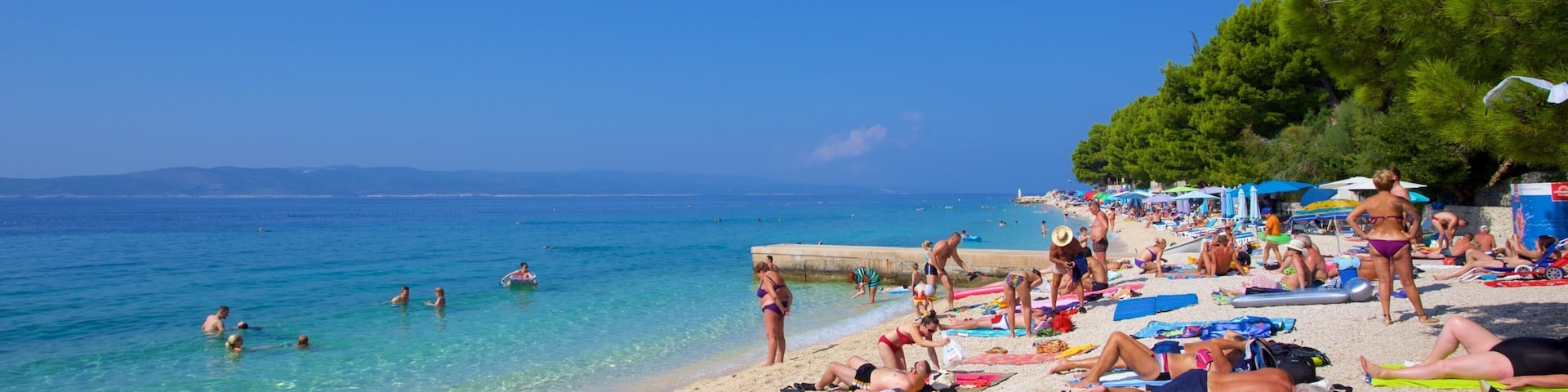 Praia de Baska Voda que inclui uma praia de pedras assim como um pequeno grupo de pessoas