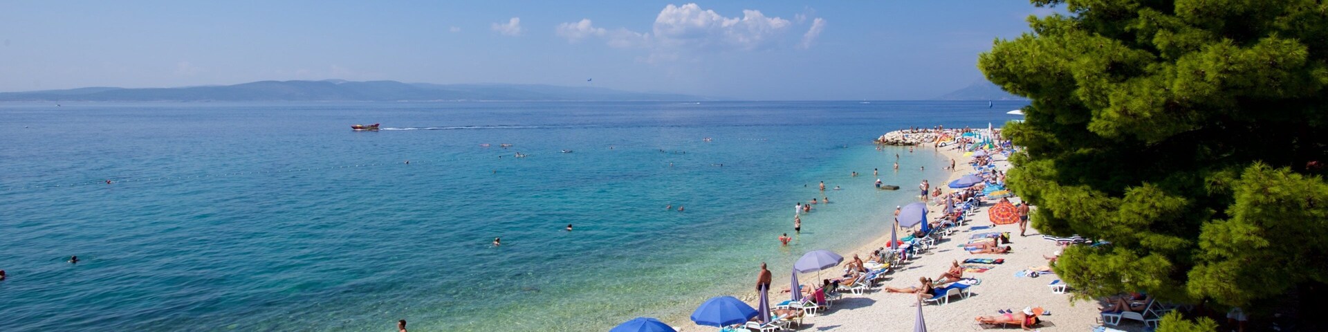 Praia de Baska Voda que inclui uma praia de pedras assim como um pequeno grupo de pessoas